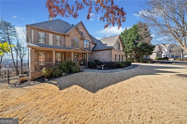 view of front of home featuring fence, covered porch, driveway, and a chimney