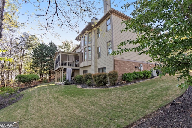 rear view of property with a chimney, an attached garage, a sunroom, a patio area, and fence