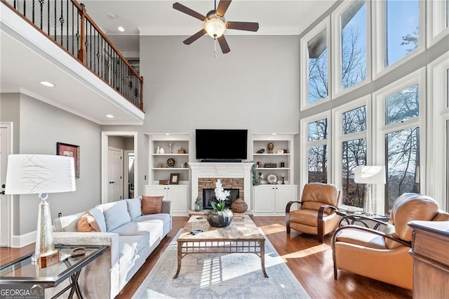 living room with a fireplace, ceiling fan, dark wood-style floors, and ornamental molding