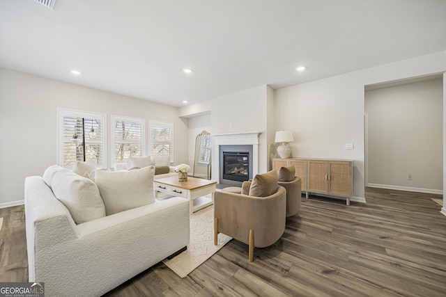 living area with a glass covered fireplace, recessed lighting, baseboards, and dark wood-style flooring