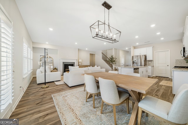 dining space featuring stairway, recessed lighting, a fireplace, and wood finished floors