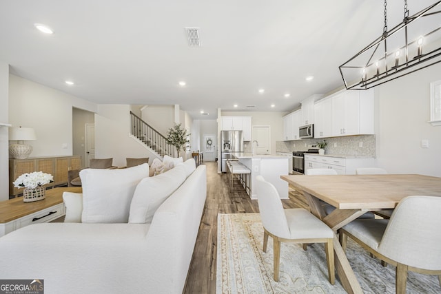 dining space featuring recessed lighting, stairway, visible vents, and light wood finished floors