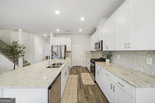 kitchen with a center island with sink, visible vents, a sink, stainless steel appliances, and dark wood-type flooring