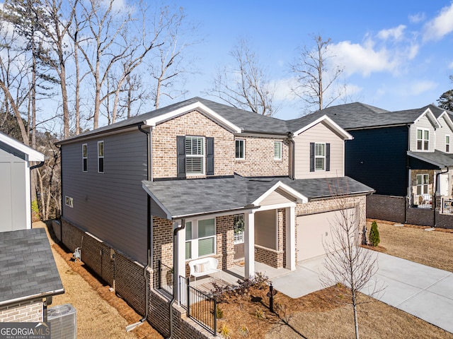 traditional-style home featuring brick siding, covered porch, concrete driveway, and fence