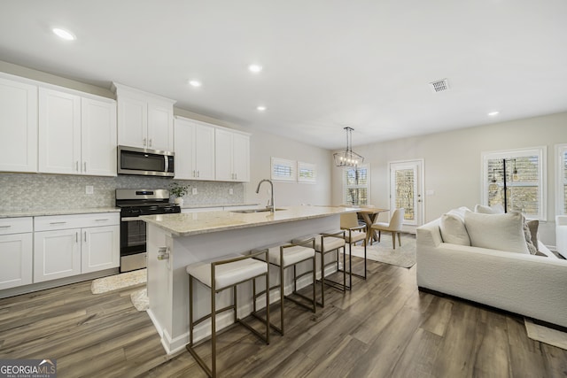 kitchen featuring a sink, stainless steel appliances, visible vents, and wood finished floors