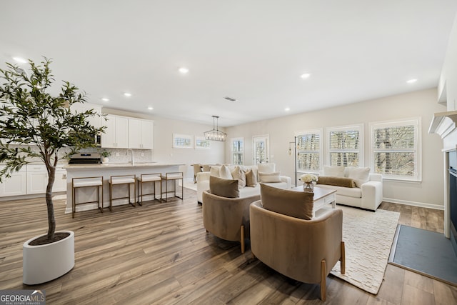 living area with visible vents, baseboards, a fireplace with flush hearth, recessed lighting, and light wood-type flooring