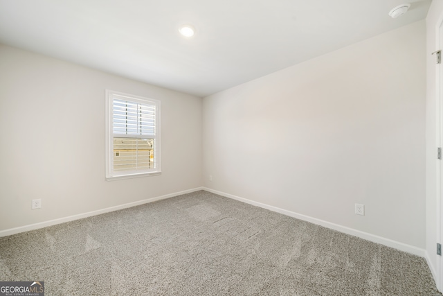 carpeted empty room featuring baseboards