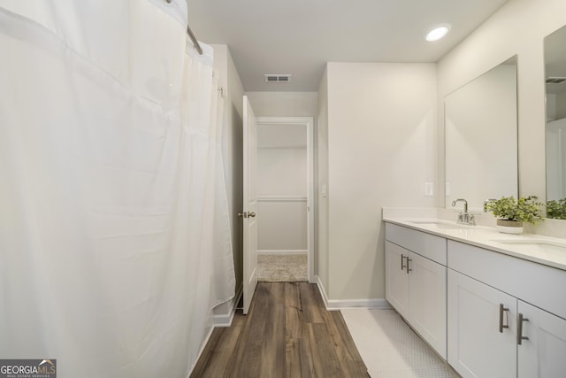 full bathroom with wood finished floors, baseboards, visible vents, double vanity, and a sink