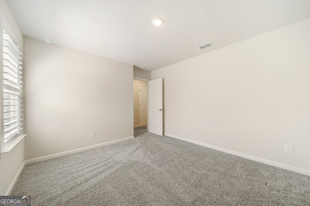 empty room featuring carpet flooring, baseboards, and visible vents