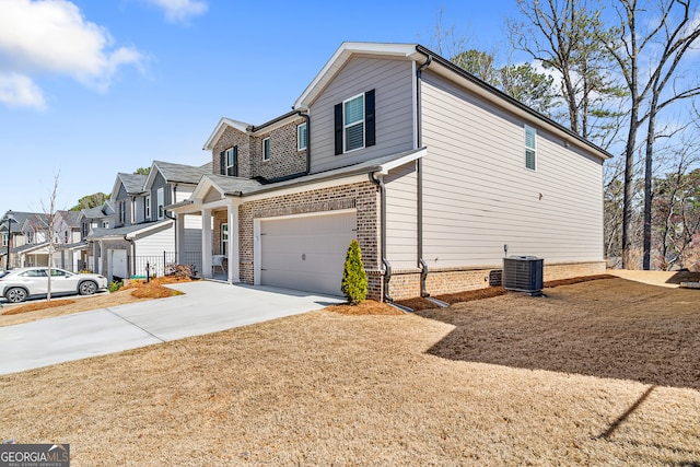 view of side of home featuring cooling unit, driveway, an attached garage, a residential view, and brick siding