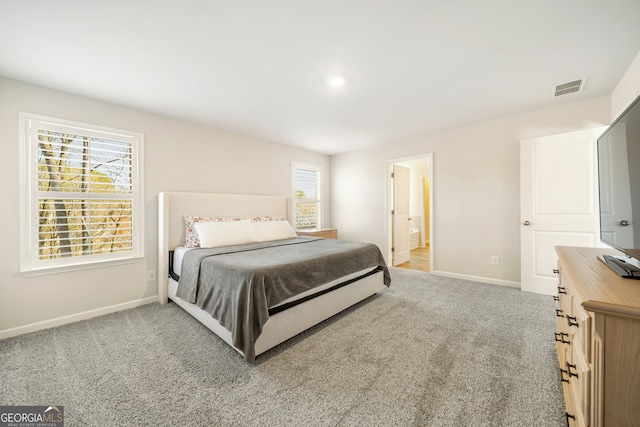 carpeted bedroom with visible vents, connected bathroom, and baseboards