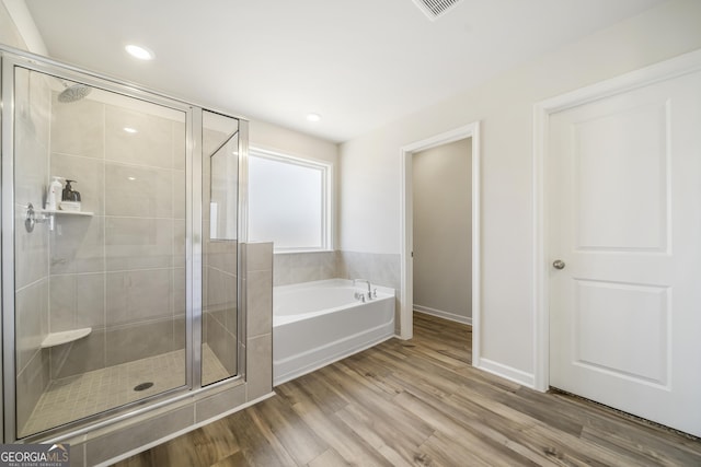 full bath with a shower stall, a bath, wood finished floors, and visible vents