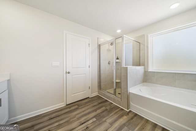 full bath with a shower stall, a garden tub, wood finished floors, and baseboards