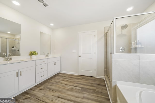 full bathroom with a sink, visible vents, wood finished floors, and a shower stall