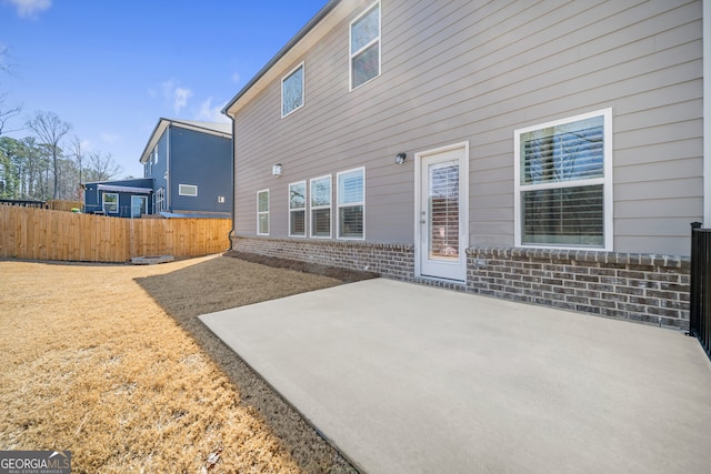 back of property with a patio, brick siding, and fence