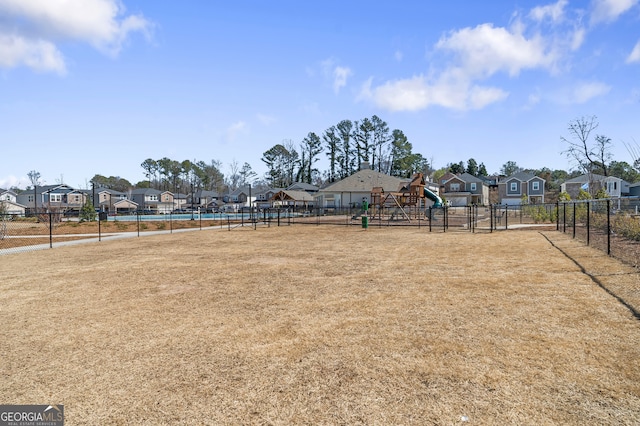 view of yard featuring playground community, a residential view, and fence