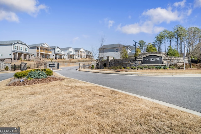 view of road featuring sidewalks, curbs, a residential view, and a gated entry