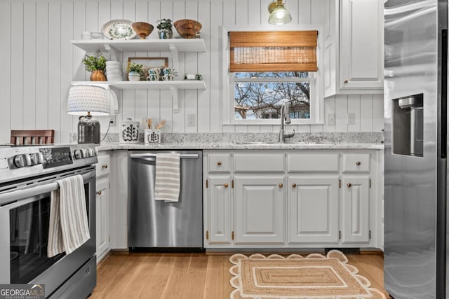 kitchen featuring open shelves, appliances with stainless steel finishes, white cabinets, and light stone counters