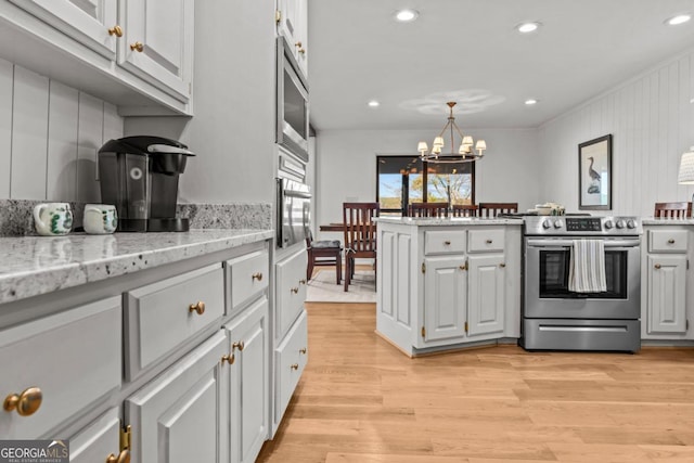 kitchen featuring light wood-type flooring, an inviting chandelier, pendant lighting, and stainless steel appliances