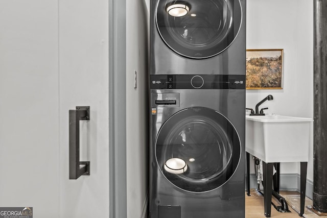 washroom with stacked washer / dryer, a sink, and light wood-style floors