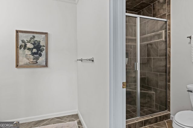 bathroom featuring toilet, a shower stall, and baseboards