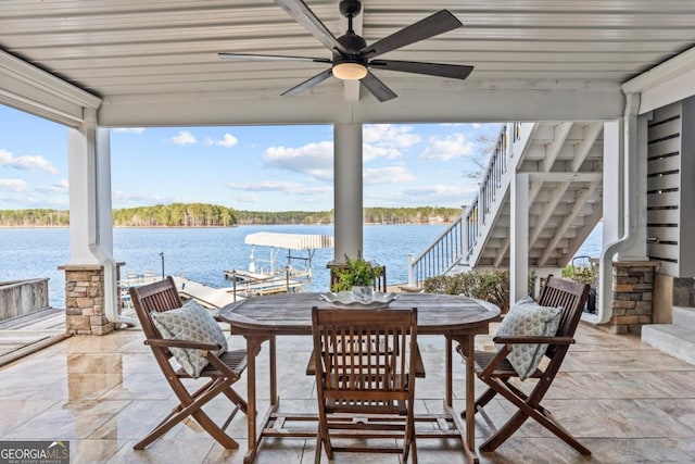 view of patio featuring ceiling fan, outdoor dining area, a water view, stairs, and a dock