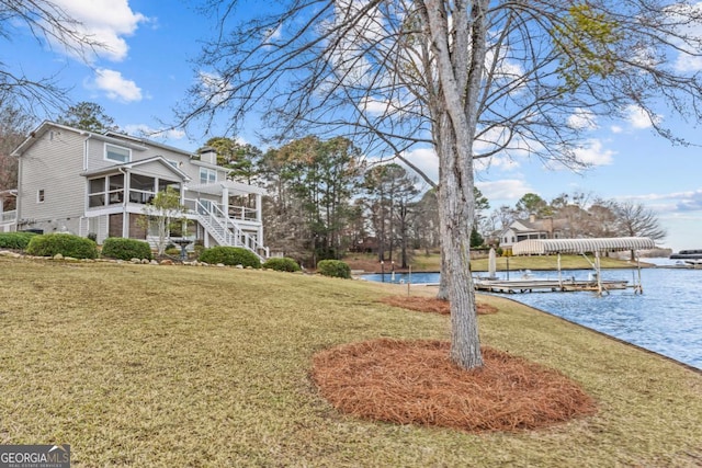 view of yard with stairway, a boat dock, a water view, and a sunroom