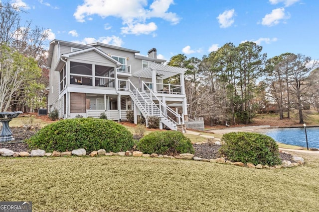 rear view of house with a water view, a sunroom, stairway, a pergola, and a chimney