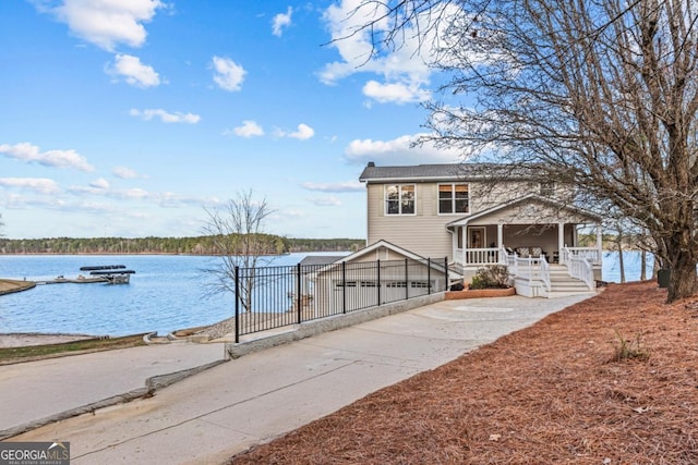 view of front of house featuring covered porch, a water view, and concrete driveway