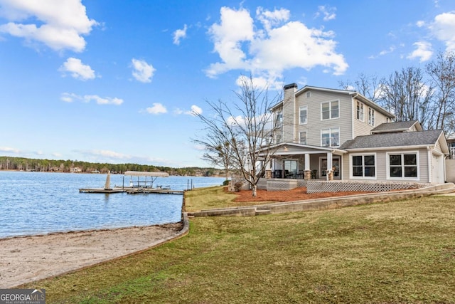 exterior space with a water view, a chimney, and a lawn