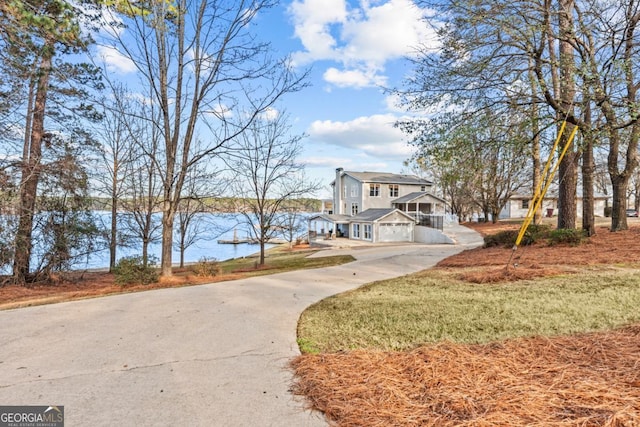 view of front facade with concrete driveway and a water view