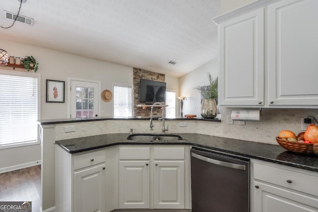 kitchen featuring visible vents, white cabinets, dishwasher, a peninsula, and a sink