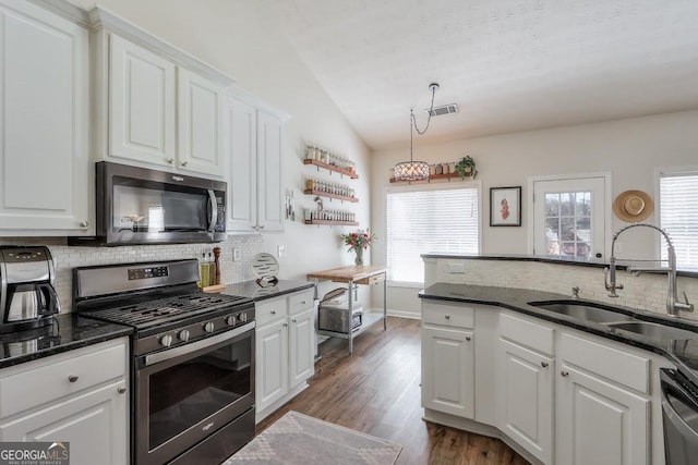 kitchen featuring lofted ceiling, stainless steel appliances, a sink, and white cabinets