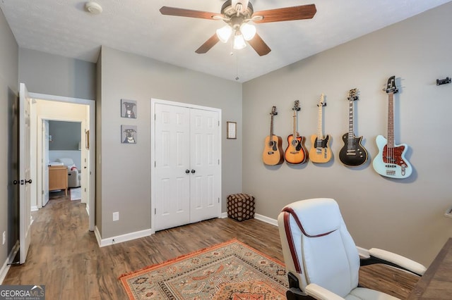 office featuring a ceiling fan, baseboards, and dark wood-type flooring