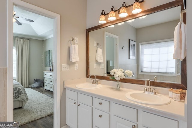 ensuite bathroom featuring double vanity, wood finished floors, a sink, and a ceiling fan