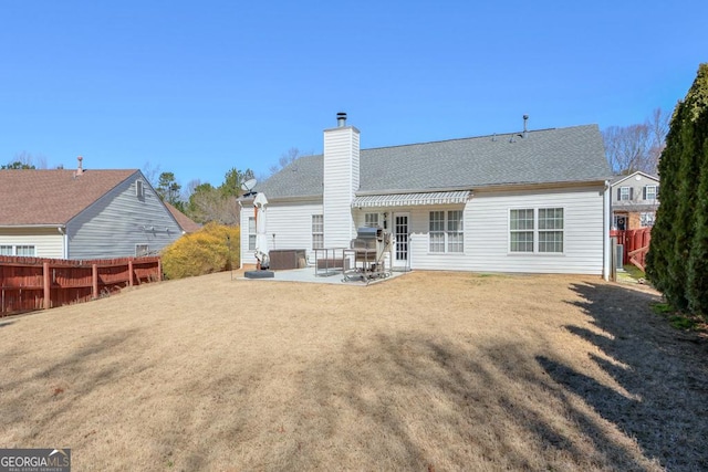 back of house featuring a yard, a patio, a chimney, and fence