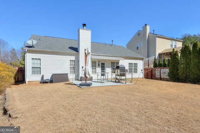 rear view of house with a yard, roof with shingles, a patio area, and fence