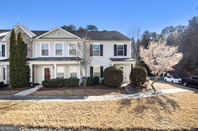 view of property with a standing seam roof, metal roof, and a front lawn