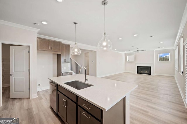 kitchen with a center island with sink, hanging light fixtures, crown molding, a fireplace, and stainless steel dishwasher