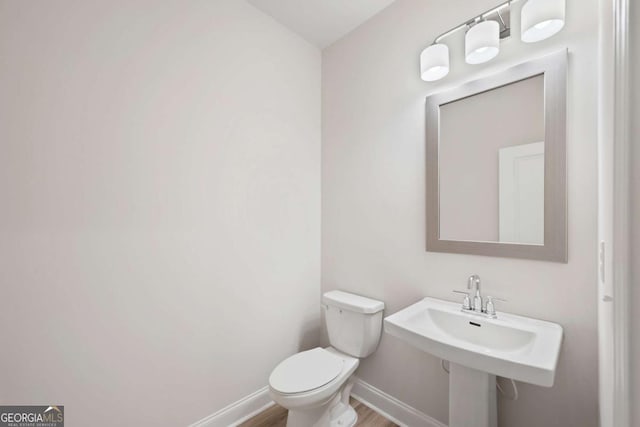 bathroom with baseboards, toilet, and wood finished floors