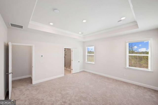 unfurnished bedroom featuring visible vents, a tray ceiling, and baseboards