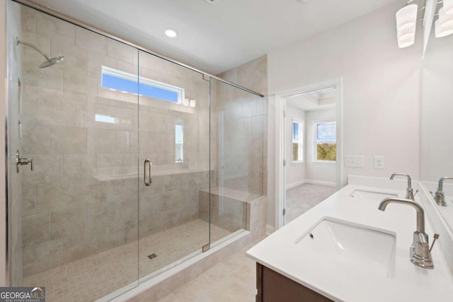 full bath with baseboards, double vanity, a sink, and a shower stall