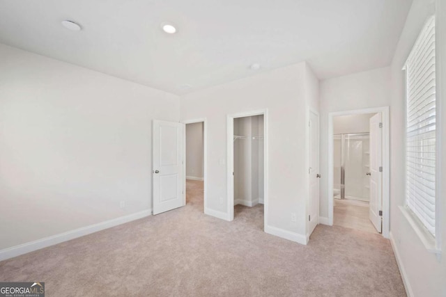 unfurnished bedroom featuring recessed lighting, light carpet, baseboards, a closet, and a walk in closet