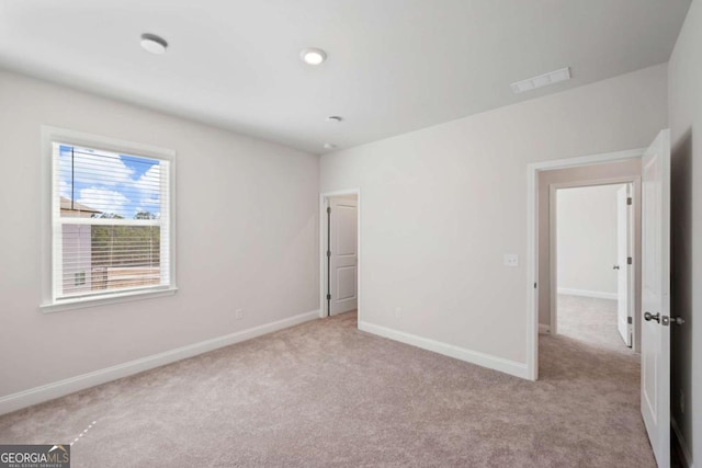 unfurnished bedroom with light carpet, visible vents, and baseboards