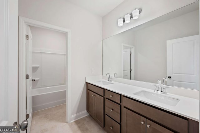 full bathroom featuring double vanity, shower / washtub combination, a sink, and baseboards