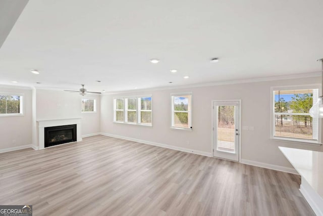 unfurnished living room featuring baseboards, a fireplace, ornamental molding, and light wood-style flooring