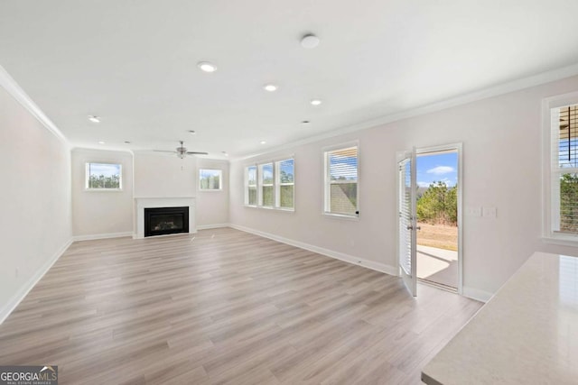 unfurnished living room with baseboards, a fireplace, light wood-style flooring, and crown molding