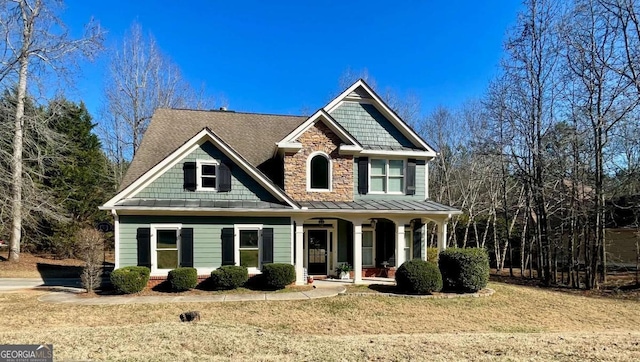 craftsman inspired home featuring stone siding, a porch, metal roof, a standing seam roof, and a front lawn