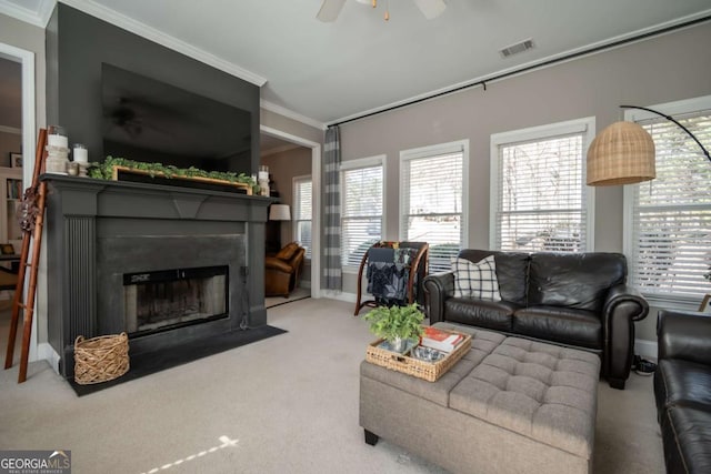 living area featuring crown molding, visible vents, a fireplace with flush hearth, light carpet, and ceiling fan