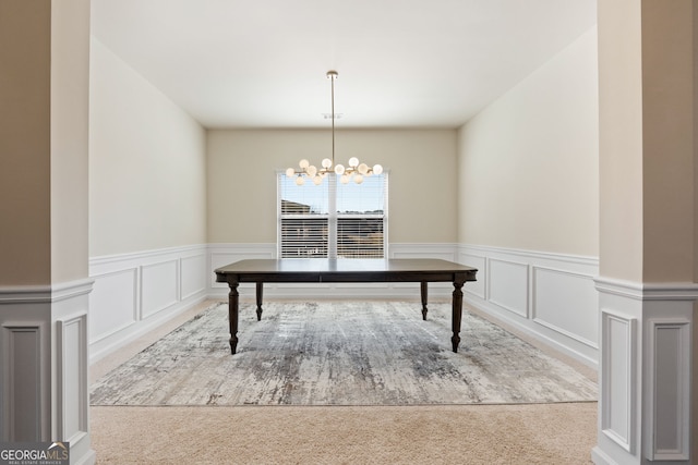 unfurnished dining area featuring a chandelier, light colored carpet, and a decorative wall